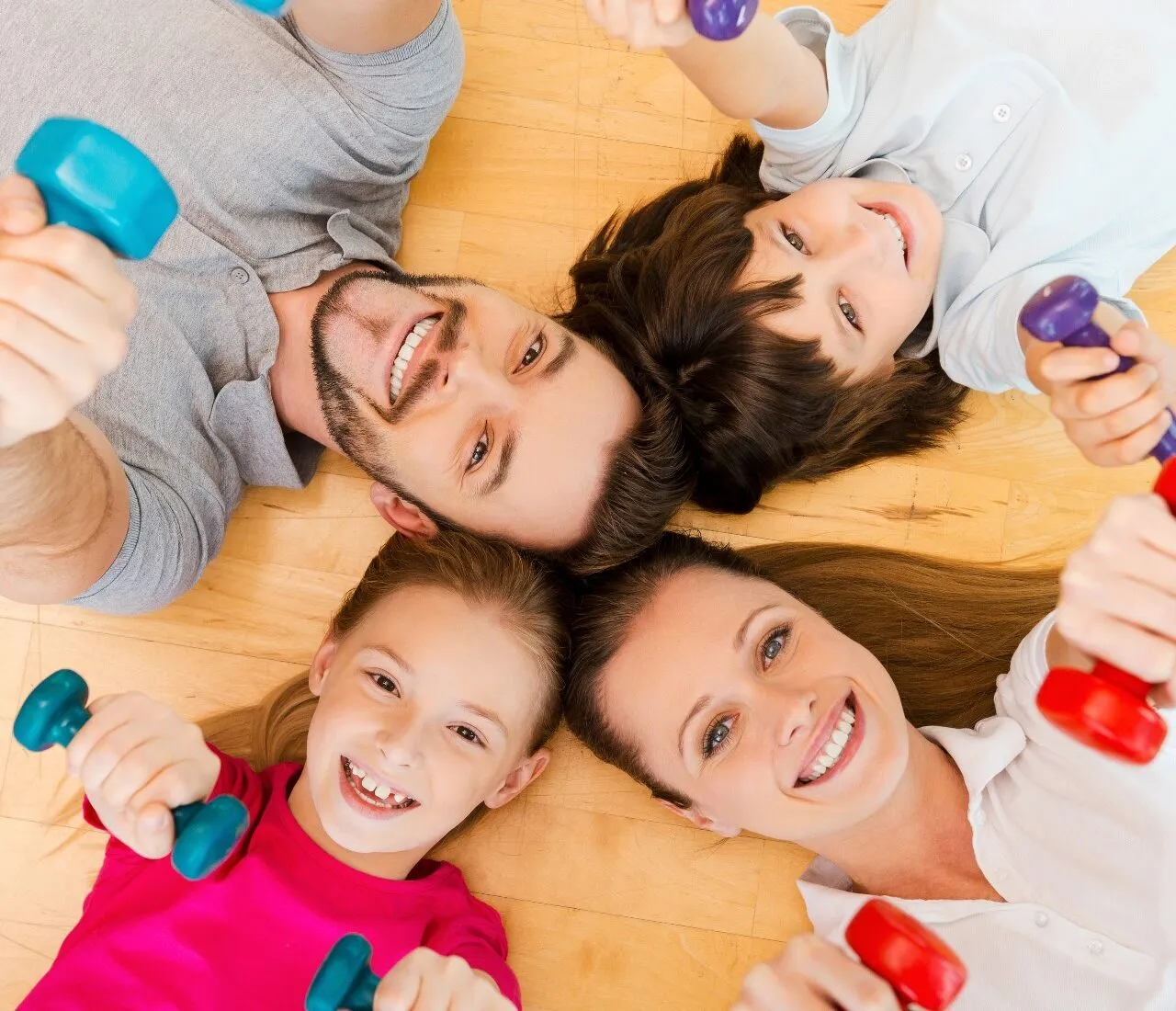 Smiling family lying on the floor with fitness weights